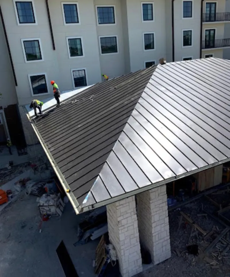 Crew installing standing seam metal roof panels on a commercial project in Hollymead